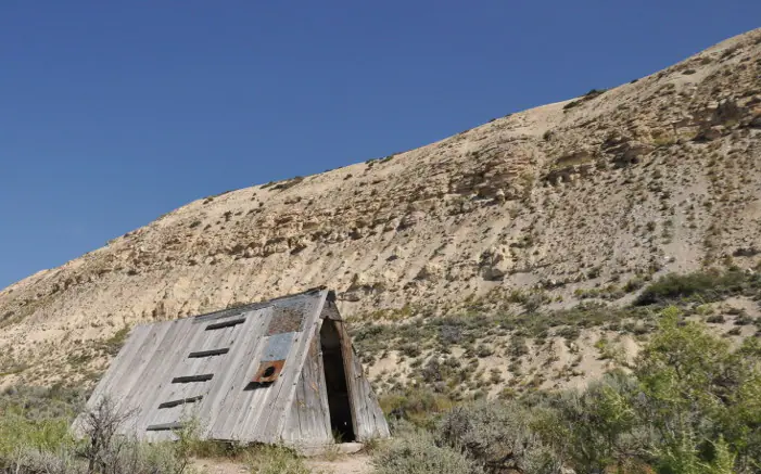 Layered Green River Formation rising behind the historic Haddenham Cabin at Fossil Butte National Monument