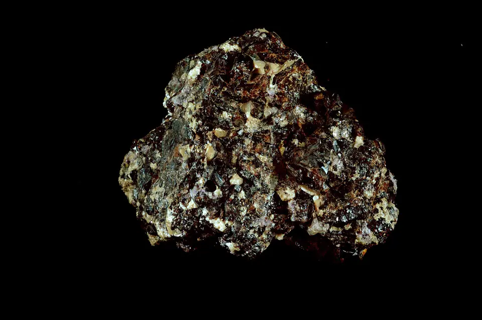 Dense cluster of dark brown lustrous cassiterite crystals in a pale mineral matrix