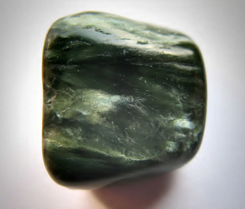 Polished green clinochlore specimen with pale feather-like seraphinite markings