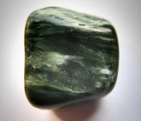 Polished green clinochlore specimen with pale feather-like seraphinite markings